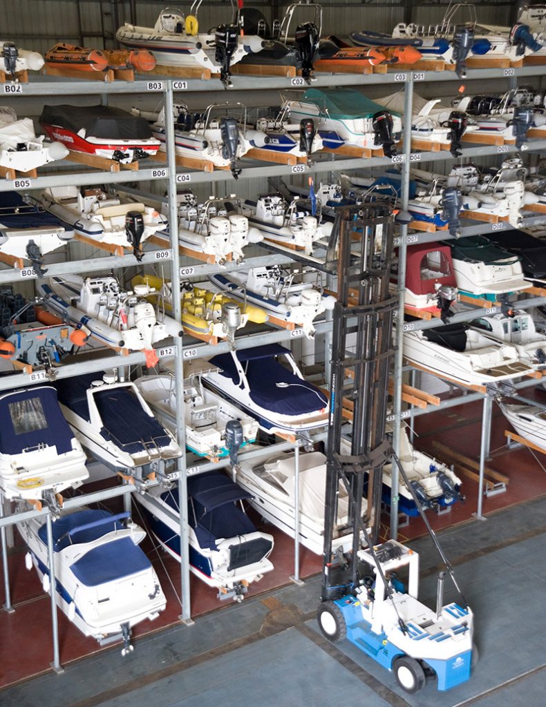 Four-high storage bays inside a Gold Key Boathouse with boats on their trailers