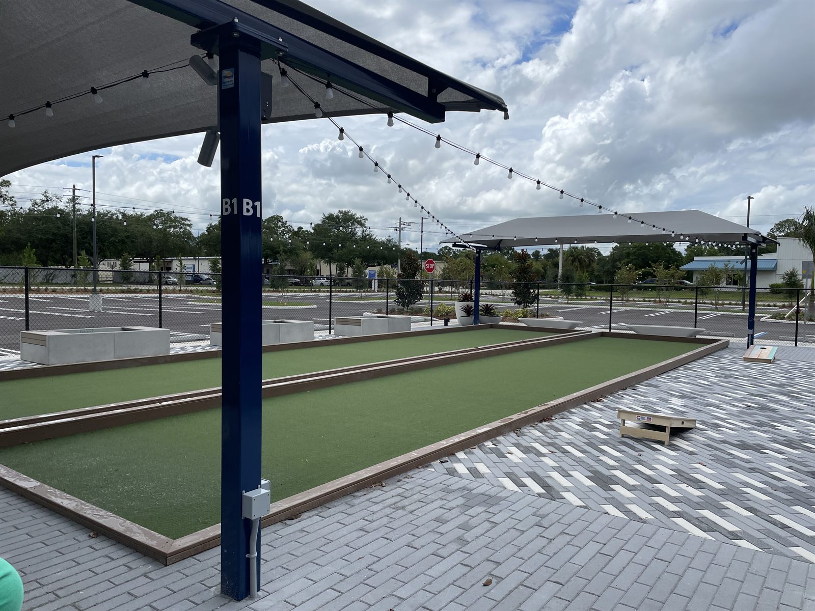 Outdoor bocce courts under shade sails and string lights